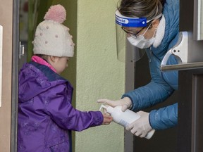 Students get their hands sanitized as they enter Ecole Marie Rose as elementary schools outside the greater Montreal area reopen Monday May 11, 2020 in St- Sauveur.