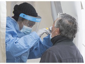 A health-care worker swabs a man at a walk-in COVID-19 test clinic in Montreal North, Sunday, May 10, 2020.