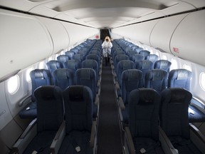 A flight attendant wears personal protective equipment as they walk through the back part of a near empty plane from Calgary which landed in Vancouver, B.C., Tuesday, June 9, 2020.