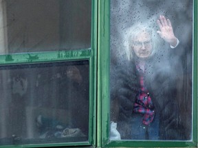 A resident waves from her window at Residence Herron, a senior's long-term care facility, following a number of deaths since the coronavirus disease (COVID-19) outbreak in Dorval on April 13, 2020.
