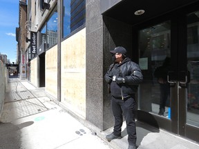 A security guard stands in the door of the boarded-up Foot Locker store on Ste-Catherine St. in Montreal June 1, 2020, after the windows were smashed by looters after a peaceful anti-racism demonstration Sunday night.