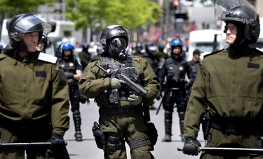 Sûreté du Québec riot squad stand on guard, with a tear gas launcher at the ready, outside the SPVM police headquarters during march against racism and police brutality in Montreal on Sunday, June 7, 2020.