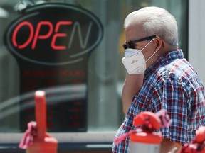 A man wearing an mask walks past a fast food restaurant on Corydon Avenue in Winnipeg on Wednesday, June 24, 2020.
