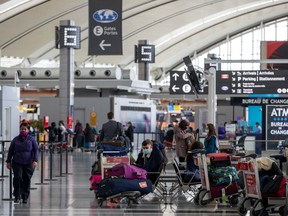 Passengers wait for flights while wearing mandatory face masks as a "Healthy Airport" initiative is launched for travel, taking into account social distancing protocols to slow the spread of the coronavirus disease (COVID-19) at Toronto Pearson International Airport in Toronto, Ontario, Canada June 23, 2020.