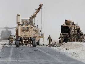 U.S. troops assess the damage to an armoured vehicle of NATO-led military coalition after a suicide attack in Kandahar province, Afghanistan, on August 2, 2017.