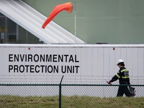 An emergency response worker carries an air monitoring device at the site of a crude oil spill at a Trans Mountain Pipeline pump station in Abbotsford, on Sunday, June 14, 2020. Trans Mountain says oil is flowing again through its pipeline after as much 190,000 litres of light crude spilled from a pumping facility in Abbotsford, B.C.