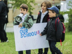 Rocco (centre) and Max Dandenault listen as Matteo Osmond chants while students, parents and teachers formed a chain around General Vanier Elementary school in St-Léonard June 5, 2019. "to save our school, raise awareness, solidarity, and raise school spirit." Their battle was ultimately unsuccessful.