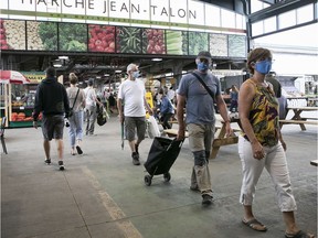 Shoppers wear their masks as they walk through the centre aisle of Jean-Talon market on Saturday June 27, 2020.
