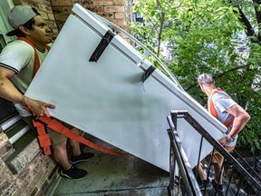 Hugh Ali and Gabriel Hernandez, left, move a fridge down a typical Montreal staircase on Quebec's moving day.