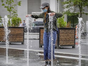 Julie Situ cools off in the fountain in Place des Festivals in Montreal Thursday July 2, 2020. (John Mahoney / MONTREAL GAZETTE)