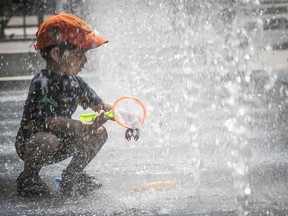 Catching his own lobster, two year-old Zayan Sajun goes fishing in the fountain at Square Victoria on Friday July 10, 2020. The city is still fighting record summer heat. (Pierre Obendrauf / MONTREAL GAZETTE)