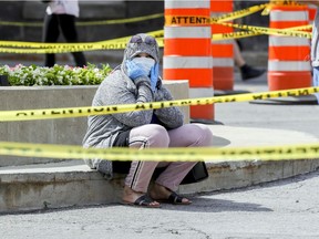 A woman sits on the base of the statue of Jeanne Mance as she waits in line for COVID-19 testing July 15, 2020.