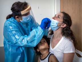 Noah watches mother Sonia Egron get a COVID-19 test from nurse May Joy De Galicia at a clinic in Outremont on July 16.