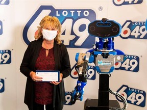 Guylaine Desjardins, who has been playing the same lottery numbers for more than 25 years, is presented with a $6-million cheque from Loto-Québec by a robot designed by a student club at the École de technology supérieure.