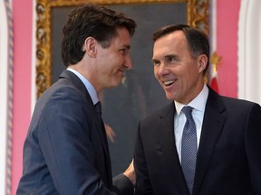 In this file photo taken on November 20, 2019, Canadian Prime Minister Justin Trudeau shakes hands with Minister of Finance Bill Morneau during a ceremony at Rideau Hall in Ottawa.