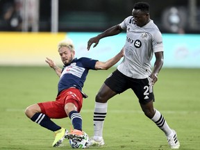 Kelyn Rowe of the New England Revolution and Victor Wanyama of Montreal Impact, right, fight for the ball during the first half in the MLS is Back Tournament at ESPN Wide World of Sports Complex on July 9, 2020, in Reunion, Fla.