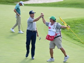 Michael Thompson of the United States celebrates with his caddie, Damian Lopez, on the 18th green after winning the 3M Open on Sunday, July 26, 2020. at TPC Twin Cities in Blaine, Minn.