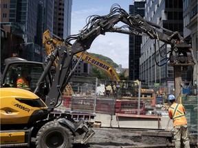 Work crews use a small pile driver to install I beams as the REM rail project and the Sainte-Catherine Street remodelling project collide at the intersection in Montreal, on Thursday, July 16, 2020.