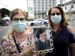 Sisters Sabina Lanzolla, left, and Nancy Lanzollo hold a picture of their mother, Giacomina Scattaglia-Lanzolla at a vigil for those that passed away from Covid-19 at Residence Angelica in Montreal, on Thursday, July 23, 2020. (Allen McInnis / MONTREAL GAZETTE)