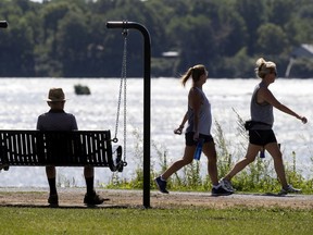 A man rests in a newly installed swinging bench in Montreal, on Tuesday, July 28, 2020. The benches are being installed along the shore of the St. Lawrence River in the LaSalle and Verdun boroughs.