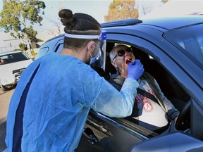 A man has a swab sample taken during testing for the COVID-19 coronavirus at a drive through pop-up venue in Melbourne on July 1, 2020. - Around 300,000 people in Melbourne were preparing to return to lockdown under the threat of fines and arrest July 1 as Australia's second-biggest city attempts to control a spike in virus cases.