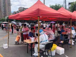 This file photo taken on July 26, 2020 shows people lining up to undergo COVID-19 coronavirus tests at a makeshift testing center in a car park in Dalian, in China's northeast Liaoning province. - China recorded 61 new coronavirus cases on July 27 -- the highest daily figure since April -- propelled by clusters in three separate regions that have sparked fears of a fresh wave. (Photo by STR / AFP) / China OUT