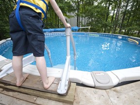 A child prepares to enter a backyard pool.