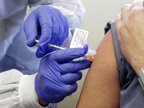 In this March 16, 2020, file photo, a subject receives a shot in the first-stage safety study clinical trial of a potential vaccine by Moderna for COVID-19, the disease caused by the new coronavirus, at the Kaiser Permanente Washington Health Research Institute in Seattle.