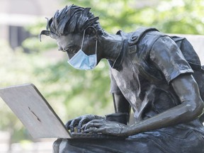 A face mask is shown on the sculpture titled La Leçon in Montreal, July 19, 2020, as the COVID-19 pandemic continues in Canada and around the world. The statue is located on Sherbrooke St. W., across from McGill University's Roddick Gates.