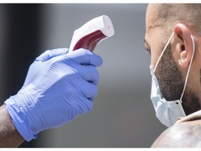 A man has his temperature checked before entering a store in Montreal July 25, 2020.