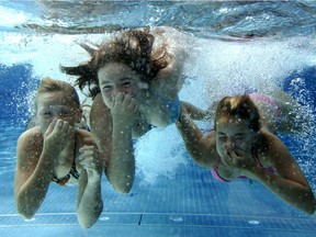 Three girls dive in a swimming pool.