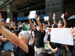 Supporters raise white paper to avoid slogans banned under the national security law as they support arrested anti-law protester outside Eastern court in Hong Kong on July 3, 2020.