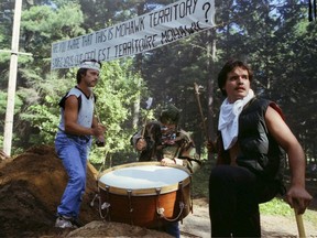 Men pound a drum near at the site of a blockade on a secondary road in Kanesatake Wednesday, July 11, 1990, the morning of the start of the Oka Crisis in Kanesatake near Montreal. The long summer of conflict began when Quebec Provincial Police attempted to forcefully dismantle the Mohawk blockade on a side dirt road that had been erected earlier in the year to protest the proposed expansion of a golf course.