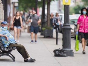 A man wears a face mask as he sits on a bench in Montreal, Saturday, June 27, 2020, as the COVID-19 pandemic continues in Canada and around the world.