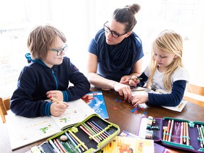 A mother helps her children do schoolwork at home in March. The absence of women with children from the workforce is critical as Canada tries to rebound from the economic hit laid by the pandemic.