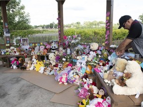 A man places a message at a memorial for Norah and Romy Carpentier, Sunday, July 12, 2020 in Lévis. The bodies of Norah and Romy Carpentier, aged 11 and 6, were found in a wooded area of a Quebec City suburb on Saturday.