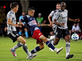 New England Revolution forward Gustavo Bou (7) kicks the ball against Montreal Impact defender Jukka Raitala (22) and defender Rod Fanni (7) during the first half at the ESPN Wide World of Sports Complex on July 9, 2020.
