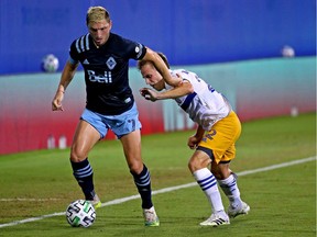 David Milinković of the Vancouver Whitecaps, left, keeps control of the ball and fends off San Jose Earthquakes forward Tommy Thompson during Wednesday's action in the MLS is Back Tournament at the ESPN Wide World of Sports Complex in Orlando, Fla. The Caps blew a 3-1 lead in the second half and lost 4-3.