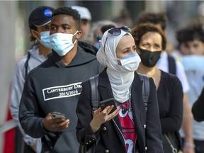 People wear masks while walking on Ste-Catherine St. in Montreal Wednesday Aug. 5, 2020.