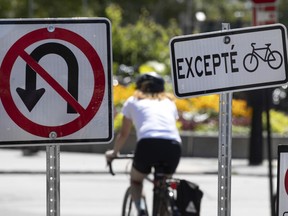 A cyclist clears a wall of roads signs as she heads to the Lachine Canal in Montreal, on Thursday, August 6, 2020. (