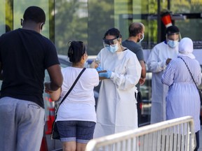 People are screened while in line at a COVID-19 testing centre in Pierrefonds Aug. 6, 2020.