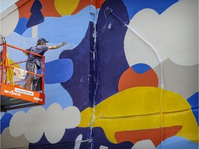 Artist Marc-Olivier Lamothe paints a mural on a wall of a building on Blvd. Saint-Laurent in Montreal Thursday August 13, 2020.