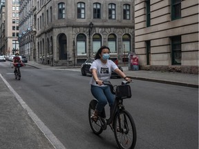 Cyclists take safety measures in Old Montreal on Thursday, August 13, 2020.