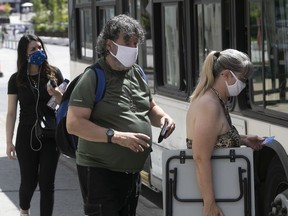 Wearing their masks, people get on the 129 STM bus at corner of Jeanne-Mance and President-Kennedy on Saturday, Aug. 22, 2020.