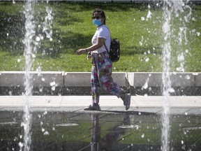 A woman walks past the fountains at Place des Festivals on Saturday August 22, 2020. (Pierre Obendrauf / MONTREAL GAZETTE)