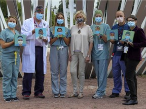 Six members of the Royal Victoria Hospital emergency room staff with artist Marja Hogan, centre, and the portraits she painted of them: from left, nurse Olivia Guay, , Dr. Robert Foxford, nurse Tery Ann Alston, Hogan, nurse Gabrielle Garrel, patient attendant Olivier Gravel and nurse Stacy Sigler with their portraits, outside the McGill University Health Centre's Glen site.