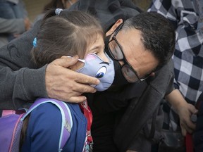 Six-year-old Tasnime Goubi gets a hug from her father, Reda Goubi, as she arrives for the first day of school at École Philippe-Labarre Aug. 27, 2020.