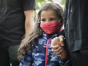 Wearing her mask, six year-old Jana Ezzine holds the hand of her mother as she waits to start her first day of Grade 1 at Philippe-Labarre Aug. 27, 2020.
