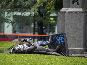 The headlessstatue of Sir John A. Macdonald lies at the base of the monument from which it was pulled during demonstration by the Coalition for BIPOC Liberation in Montreal on Saturday, Aug. 29, 2020.