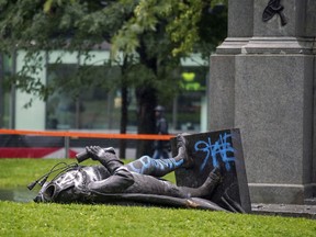 The headless body of the statue of Sir John A. Macdonald lies at the base of the monument from which it was pulled during a demonstration by the Coalition for BIPOC Liberation in Montreal on Saturday, Aug. 29, 2020.